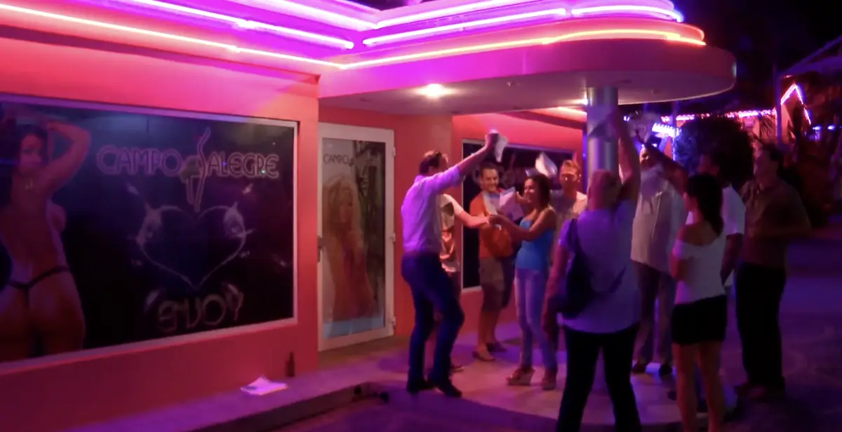 Gijs Bodenstaff, links in het witte shirt, danst met figuranten en DushiDeals-bonnen voor de ingang van Campo Alegre op Curaçao, 2016
